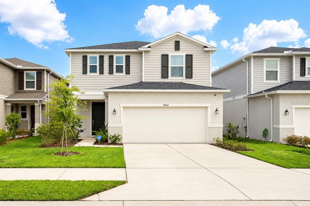 A two-story suburban house with a beige stucco and siding exterior and a two-car garage — 37402 YUKON DRIVE, ZEPHYRHILLS, FL