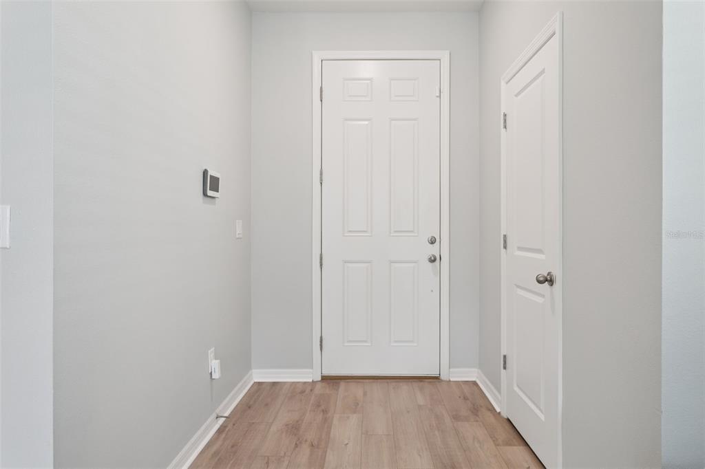 A small entryway features light gray walls, wood-look flooring, a white door, and a closet — 37402 YUKON DRIVE, ZEPHYRHILLS, FL