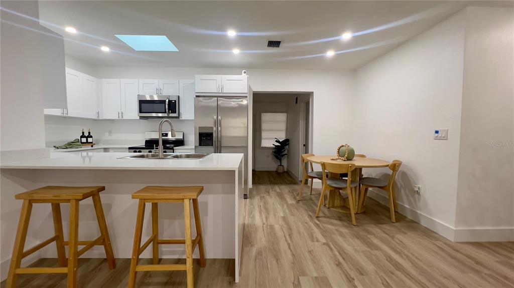 A kitchen with white cabinets, stainless steel appliances, and a dining area with wooden furniture — 22011 CATHERINE AVENUE, PORT CHARLOTTE, FL