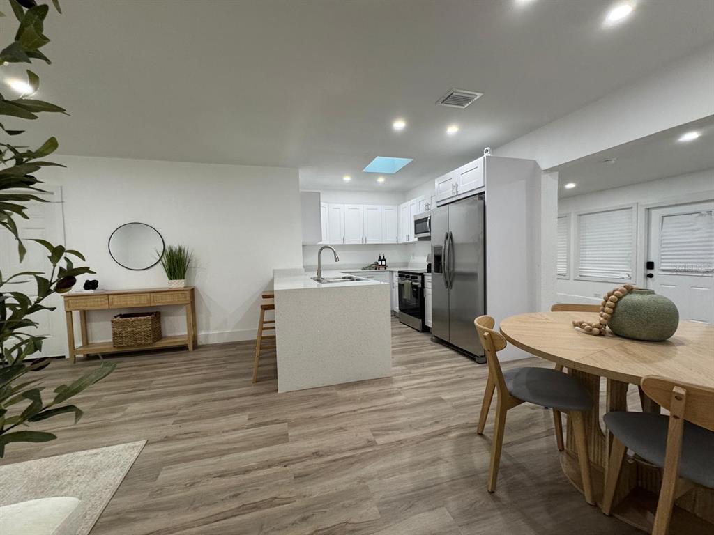 A modern kitchen with white cabinetry and a quartz island opens to a dining area — 22011 CATHERINE AVENUE, PORT CHARLOTTE, FL
