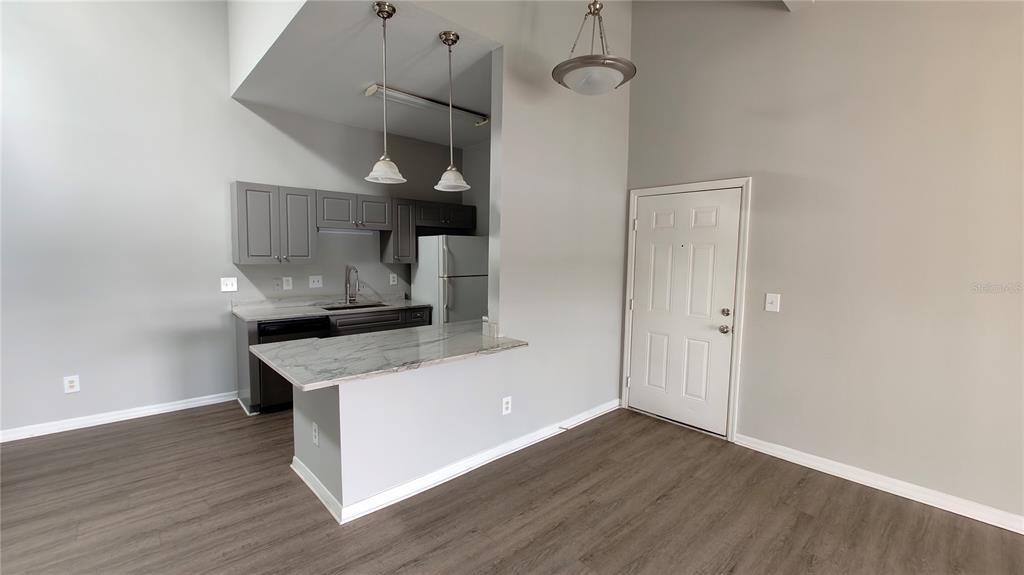 A kitchen features gray cabinets, stainless steel appliances, a white refrigerator, and a breakfast bar — 145 N PEARL LAKE CAUSEWAY UNIT 204, ALTAMONTE SPRINGS, FL