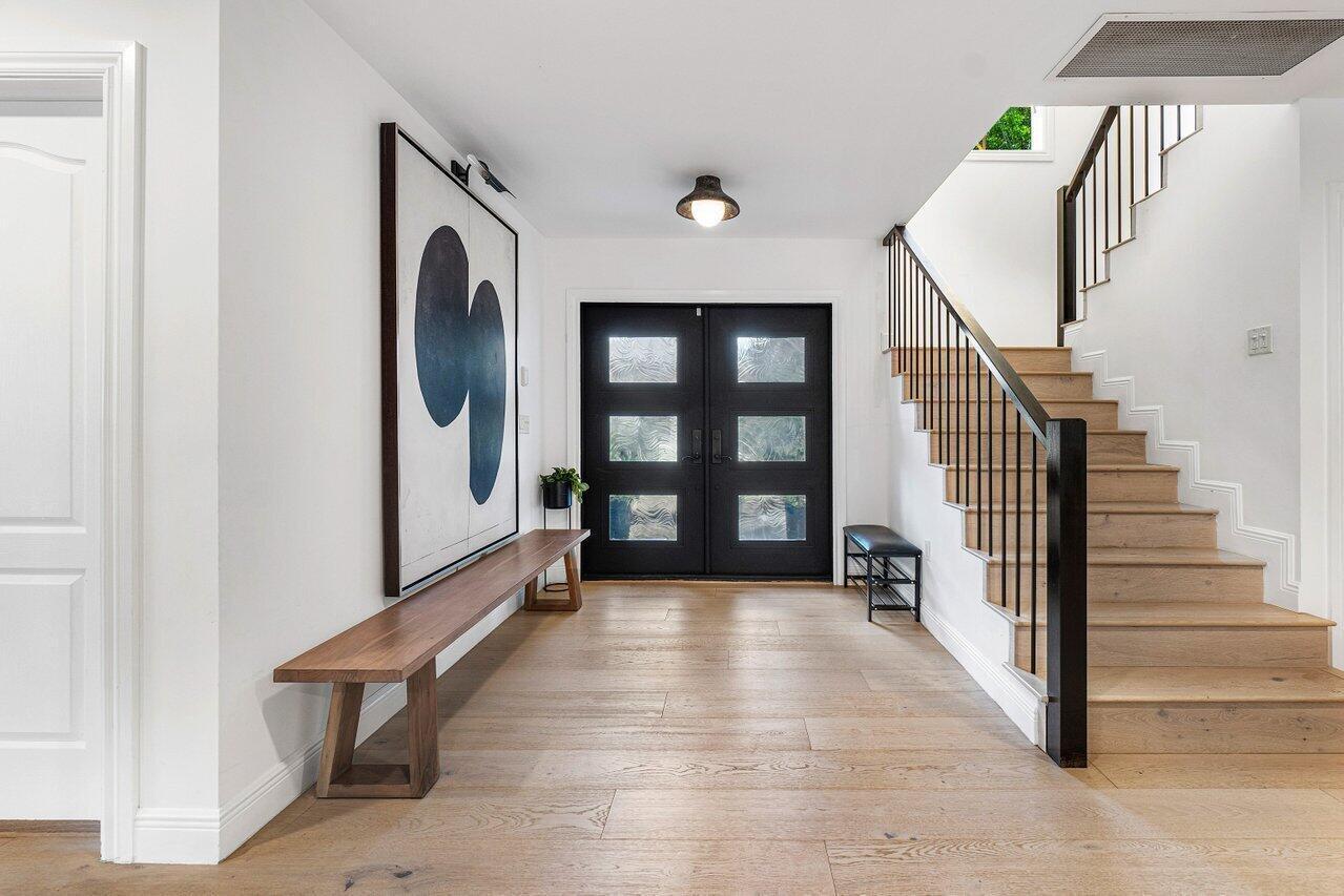 A bright entryway features light wood floors, a modern staircase, and a black double door — 783 Toledo Drive, Boca Raton FL 33432, BOCA RATON, FL