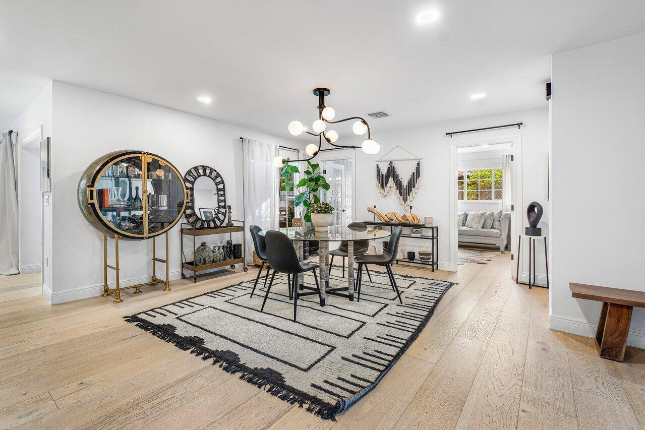 A dining room features a glass table, modern chandelier, area rug, and a circular bar cabinet — 783 Toledo Drive, Boca Raton FL 33432, BOCA RATON, FL