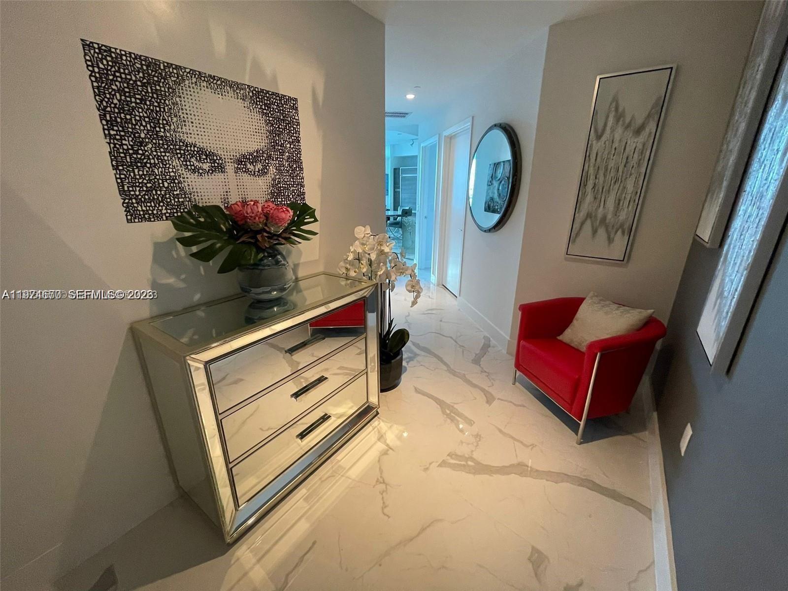 A hallway features marble floors, a mirrored dresser, a red chair, and modern wall art — 1100 S Miami Ave # 4201, Miami FL 33130, MIAMI, FL