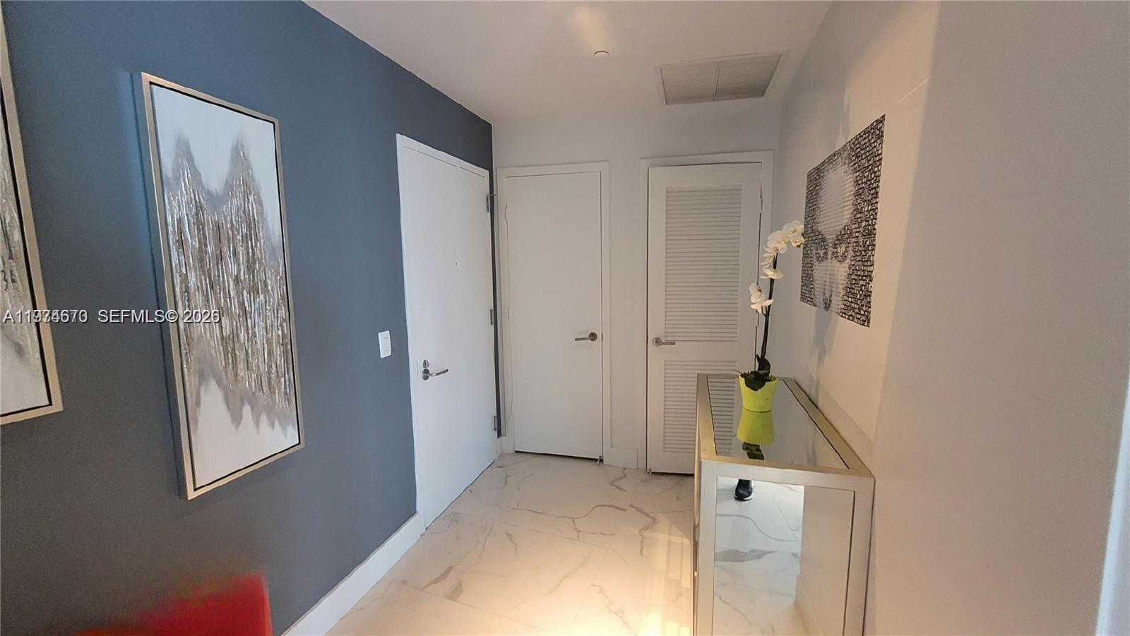 A hallway features white tile floors, a blue accent wall, and three white doors — 1100 S Miami Ave # 4201, Miami FL 33130, MIAMI, FL