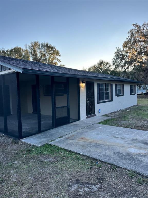 A single-story house with a screened-in porch, light-colored siding, and a dark shingled roof — 2863 COUNTY ROAD 238 UNIT 238, WILDWOOD, FL