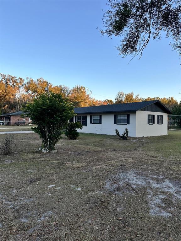 A single-story white house with a dark roof sits on a grassy lot — 2863 COUNTY ROAD 238 UNIT 238, WILDWOOD, FL