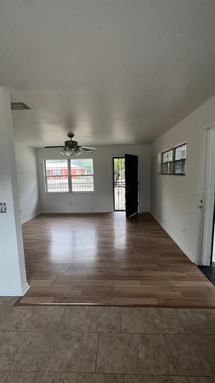 An open living area features wood-look flooring, a ceiling fan, and a black entry door — 2863 COUNTY ROAD 238 UNIT 238, WILDWOOD, FL