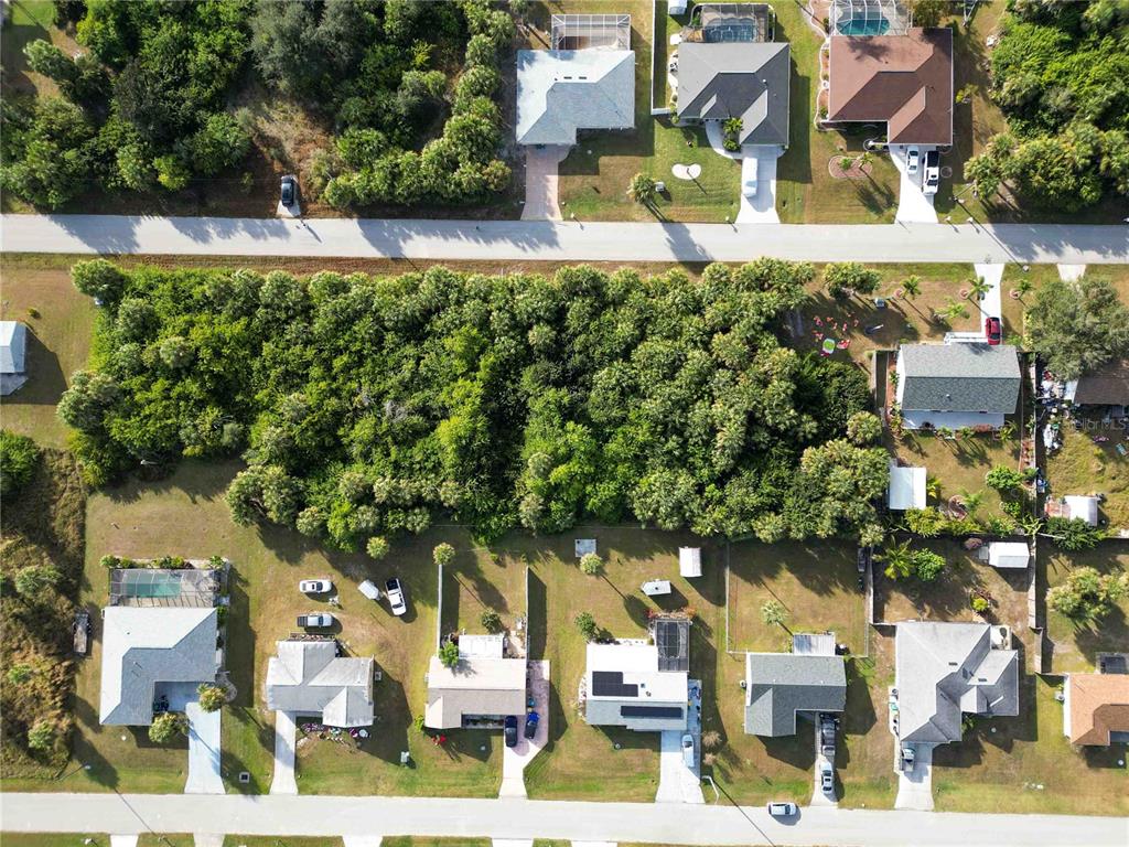An aerial view shows a large, wooded vacant lot situated between two rows of houses — 18707 ASHCROFT CIRCLE, PORT CHARLOTTE, FL