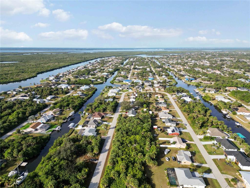 An aerial view shows a residential neighborhood with houses situated along canals and dense vegetation — 18707 ASHCROFT CIRCLE, PORT CHARLOTTE, FL
