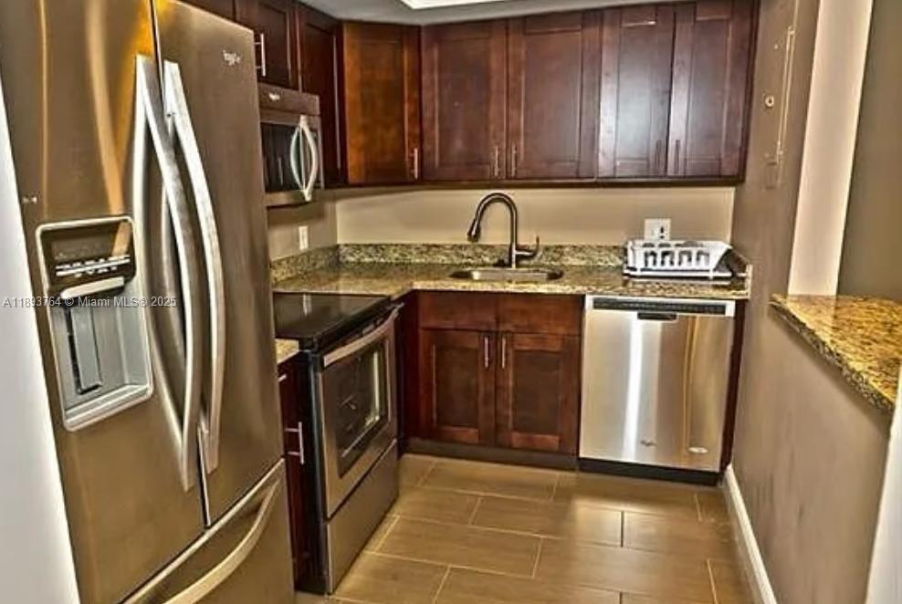 A kitchen features dark wood cabinets, stainless steel appliances, and granite countertops — 5570 NW 44th St # 312A, Lauderhill FL 33319, LAUDERHILL, FL