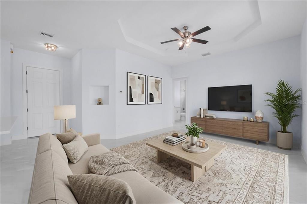 A bright living room features a beige sofa, a wooden media console, and a rug — 1927 RICHMOND AVENUE N, LEHIGH ACRES, FL
