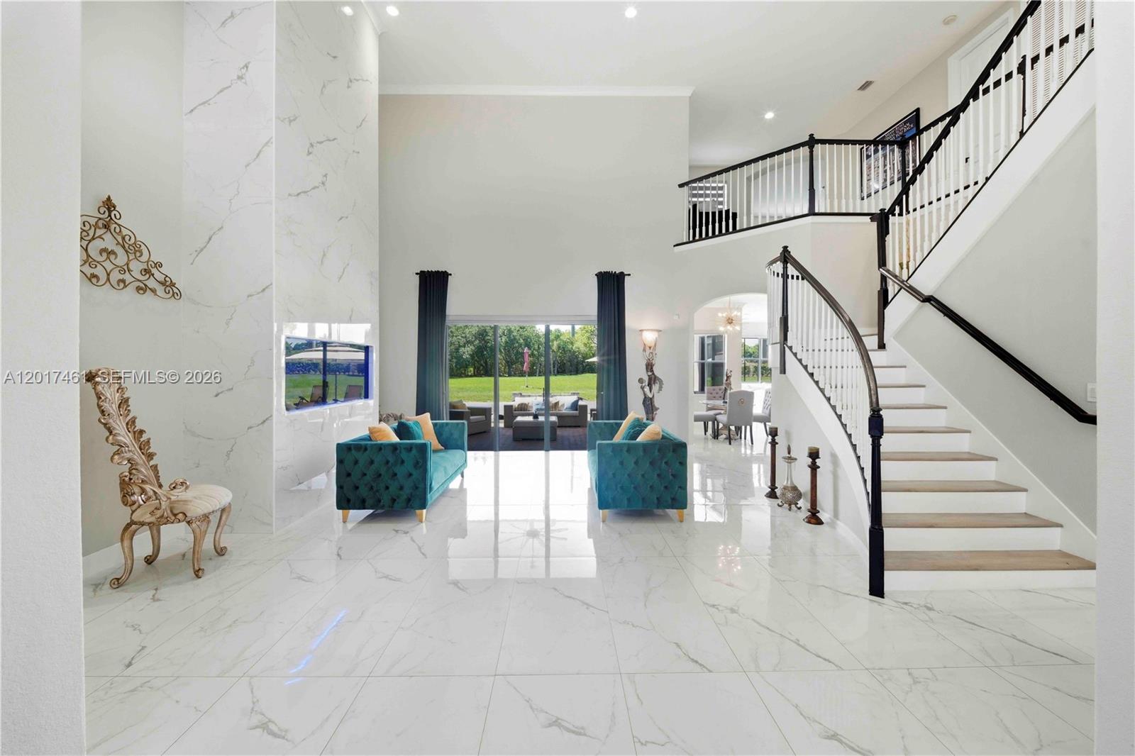 A high-ceilinged living room features white marble floors, a fireplace, and a grand staircase — 1748 SW 195th Ave, Miramar FL 33029, MIRAMAR, FL