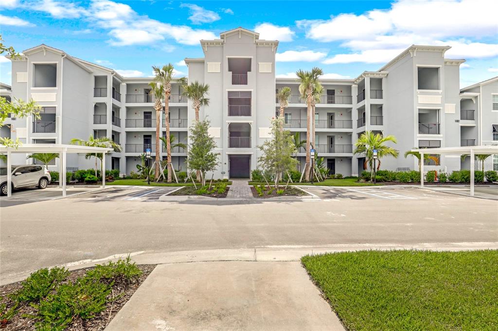 A multi-story apartment building with a central entrance, balconies, and covered parking spaces — 14061 HERITAGE LANDING BOULEVARD UNIT 444, PUNTA GORDA, FL