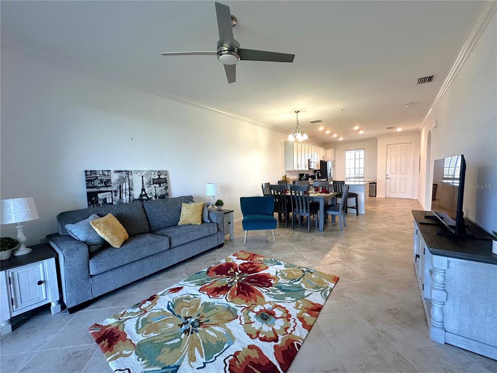 An open-concept living and dining area features tile flooring, a gray sofa, and a floral rug — 14061 HERITAGE LANDING BOULEVARD UNIT 444, PUNTA GORDA, FL