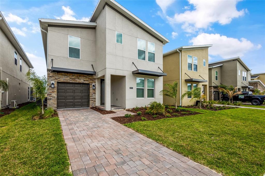 A two-story house with a stone-accented garage, paved driveway, and light-colored stucco exterior — 8931 TAKEAWAY WAY, DAVENPORT, FL