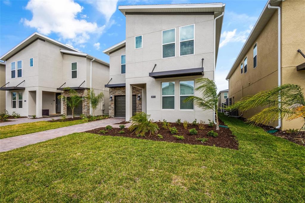 A two-story modern house with a light-colored stucco exterior and a small front yard — 8931 TAKEAWAY WAY, DAVENPORT, FL