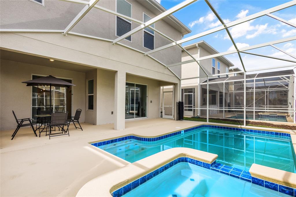 A screened-in patio features a swimming pool, a hot tub, and outdoor dining furniture — 8931 TAKEAWAY WAY, DAVENPORT, FL