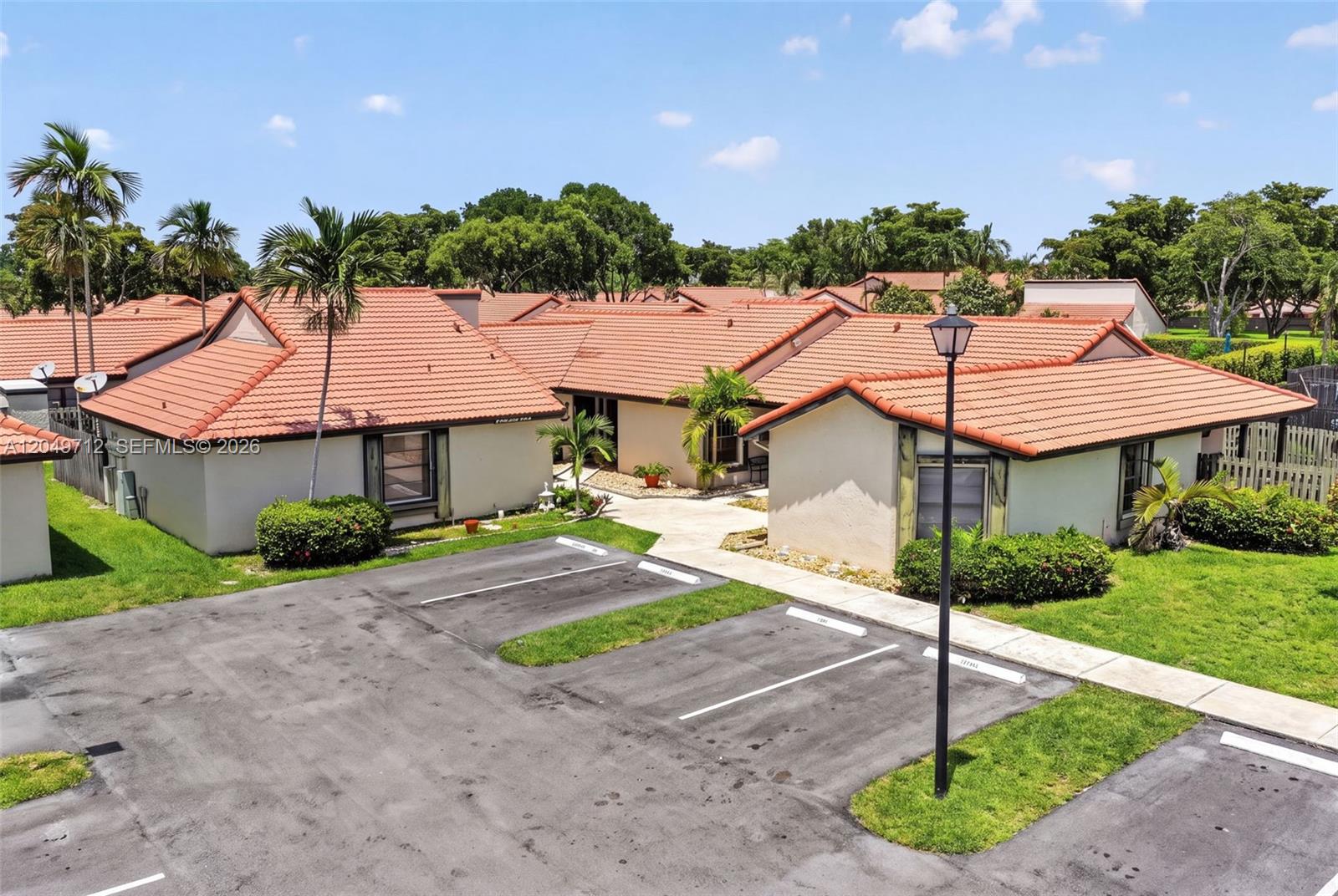 An exterior view of a single-story residential building with a tile roof and parking spaces — 15065 SW 49th Ln # F, Miami FL 33185, MIAMI, FL