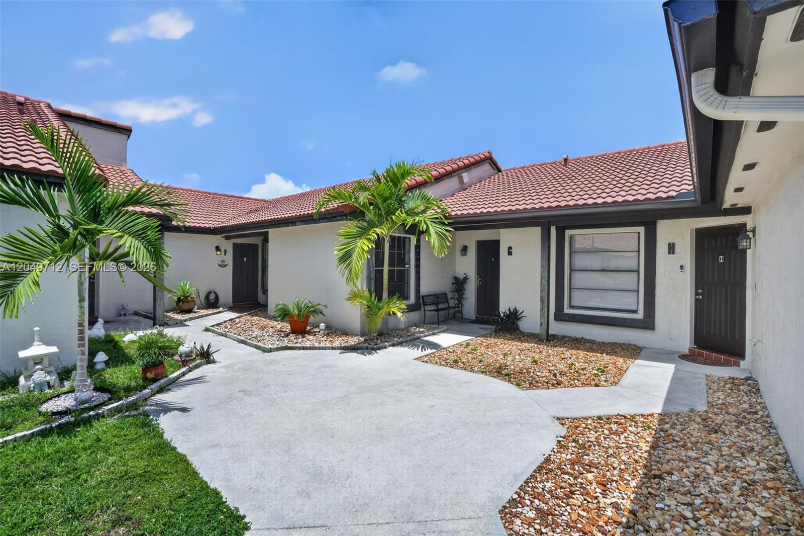 An exterior view of a residential building with three unit entrances, palm trees, and landscaping — 15065 SW 49th Ln # F, Miami FL 33185, MIAMI, FL