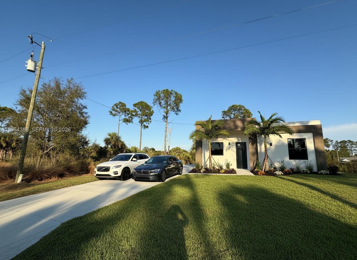 A modern one-story house with a concrete driveway and two parked cars sits on a lawn — 133 Nacelle ave, Lehigh Acres FL 33974, LEHIGH ACRES, FL