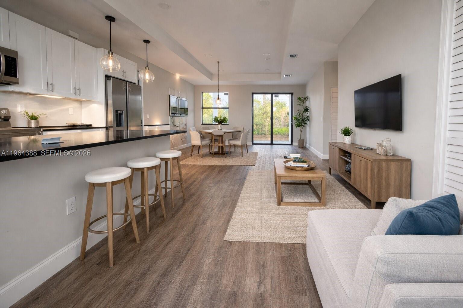 This open-concept living area features a kitchen with bar seating, a dining space, and flooring — 133 Nacelle ave, Lehigh Acres FL 33974, LEHIGH ACRES, FL