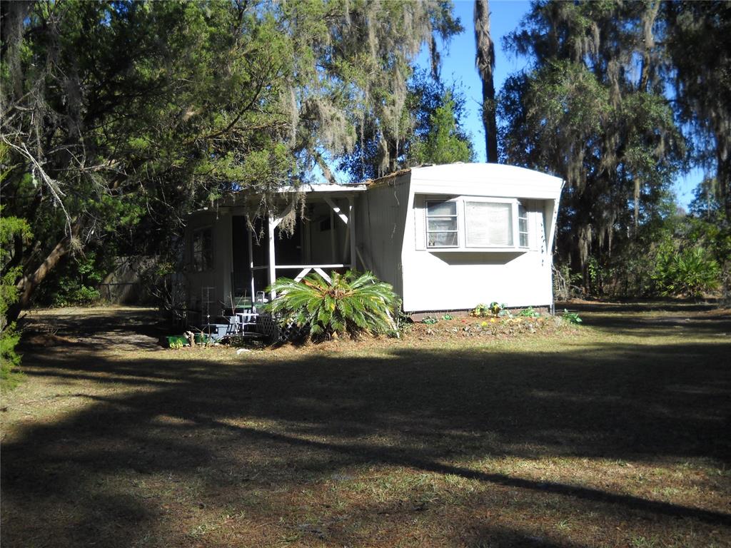 A white mobile home sits on a grassy lot surrounded by trees with Spanish moss — 4881 NW 69TH STREET, OCALA, FL