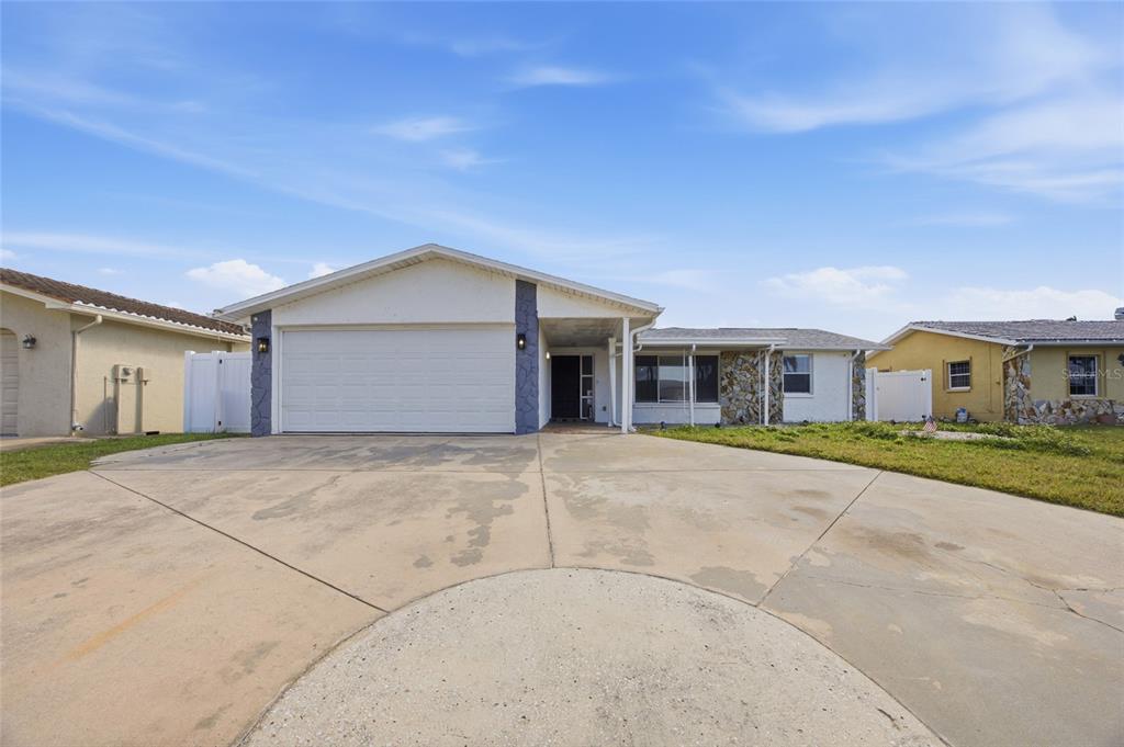A single-story house with a white garage, stone accents, and a concrete driveway — 3928 RUDDER WAY, NEW PORT RICHEY, FL