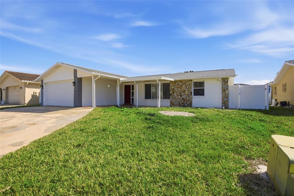 A single-story house with a white exterior, stone accent wall, and a two-car garage — 3928 RUDDER WAY, NEW PORT RICHEY, FL