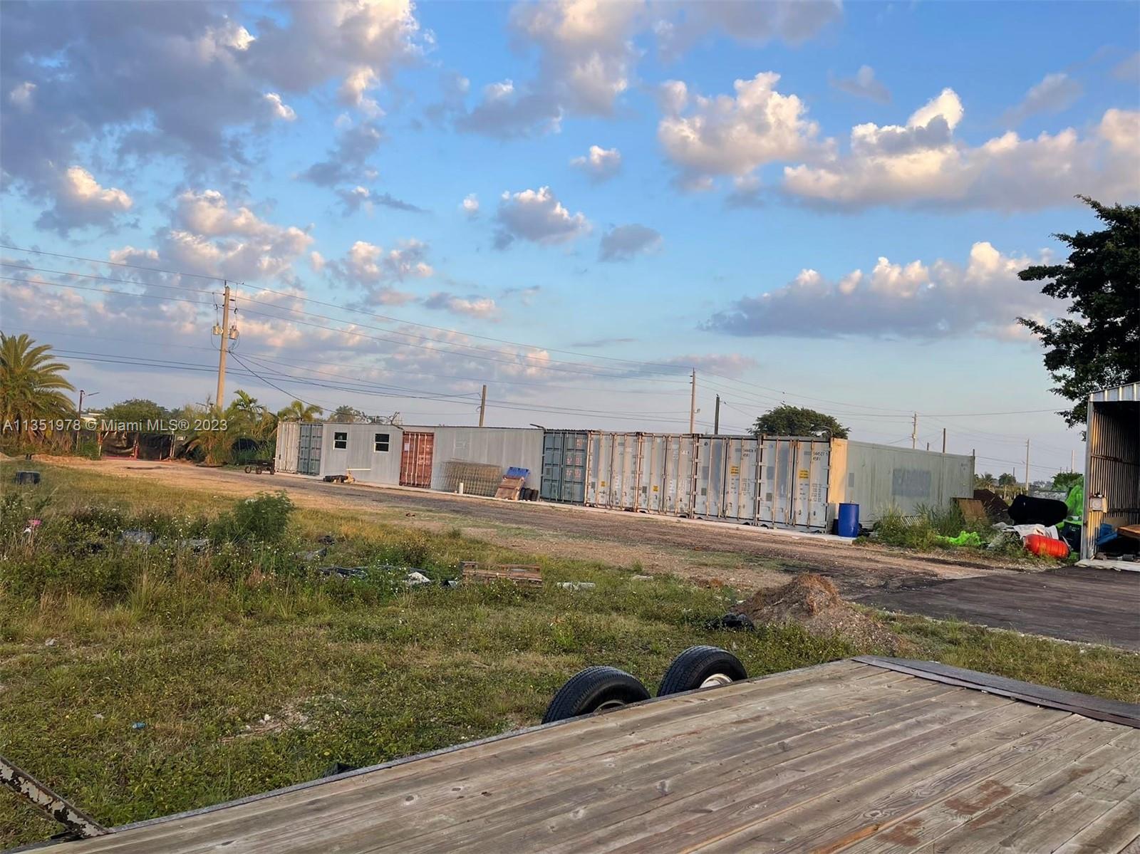 A row of shipping containers sits on a dirt lot under a cloudy blue sky — 17801 SW 197 Ave, Miami FL 33187, MIAMI, FL