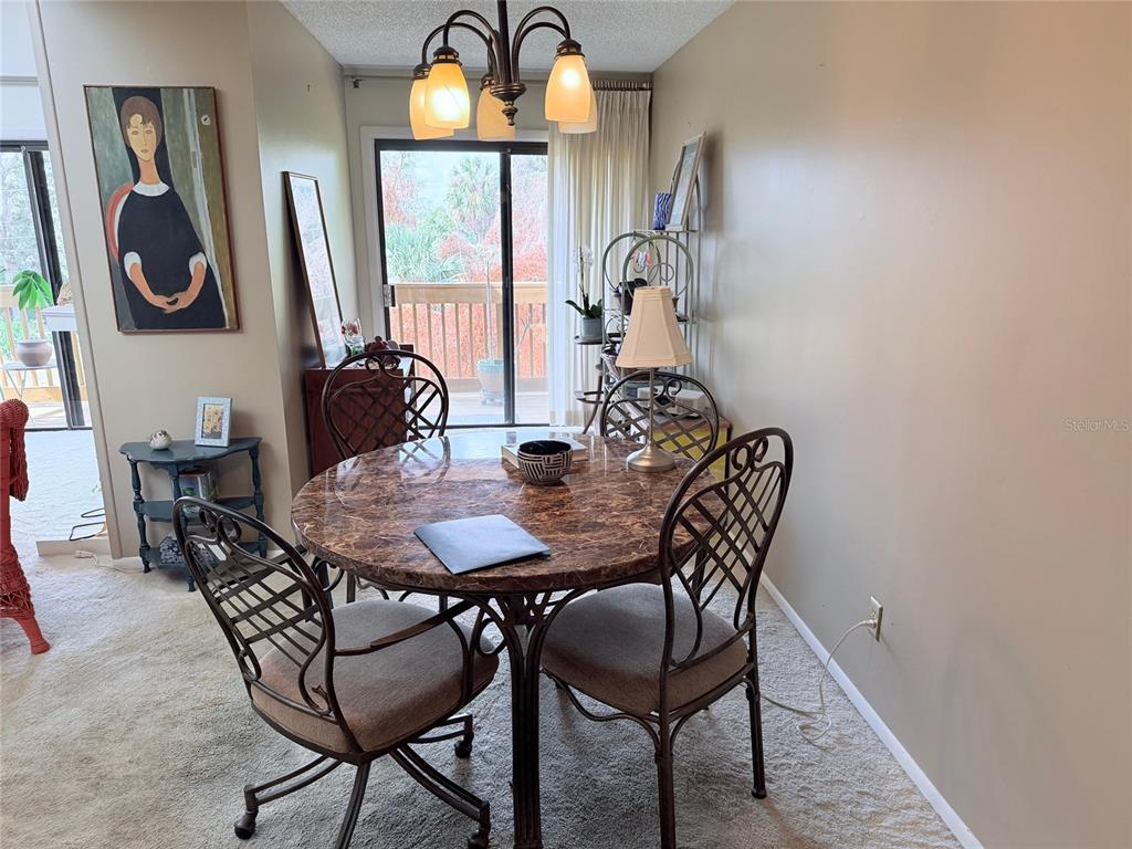 A dining area features a round marble-topped table, metal chairs, and a sliding glass door — 1051 S HIGHLAND STREET UNIT 3D, MOUNT DORA, FL