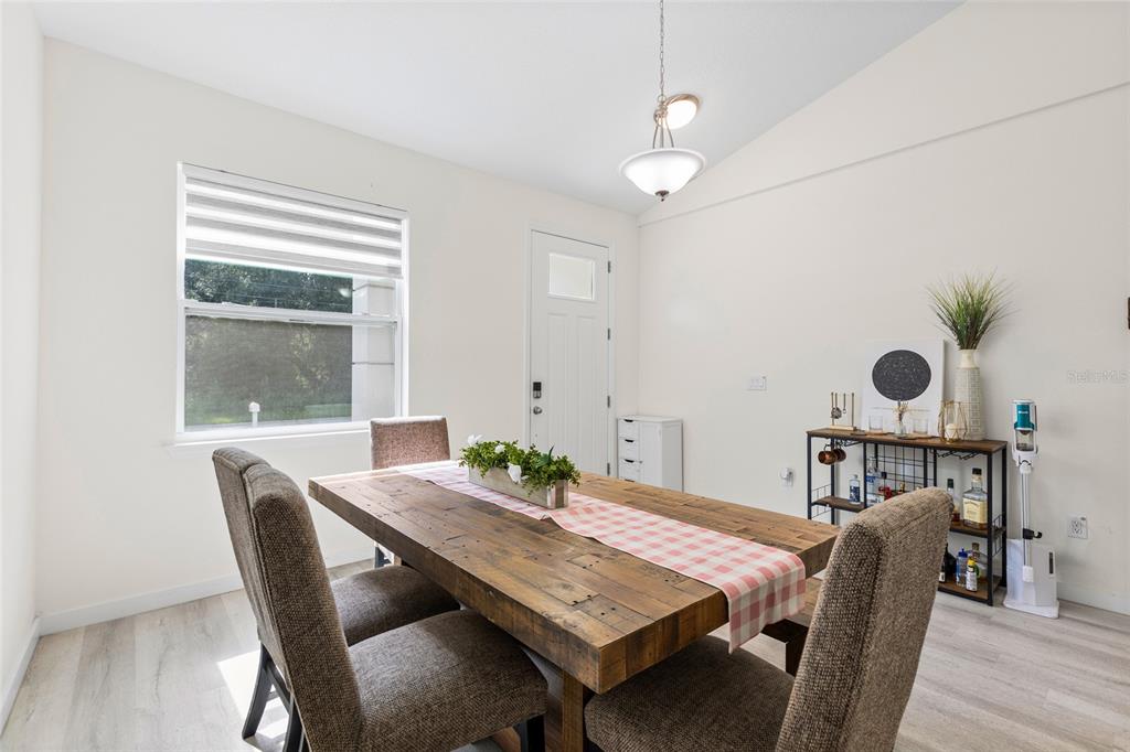 A dining room features a wooden table, four upholstered chairs, a light fixture, and a window — 1747 S OAK STREET, SEFFNER, FL