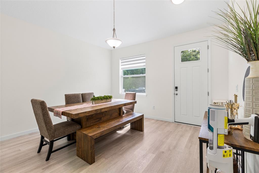 A dining room features a wooden table with a bench, chairs, and light-colored flooring — 1747 S OAK STREET, SEFFNER, FL