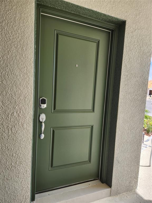 A green, two-panel front door with a smart lock and handle set in a stucco wall — 997 WATERFALL BOULEVARD, DAVENPORT, FL