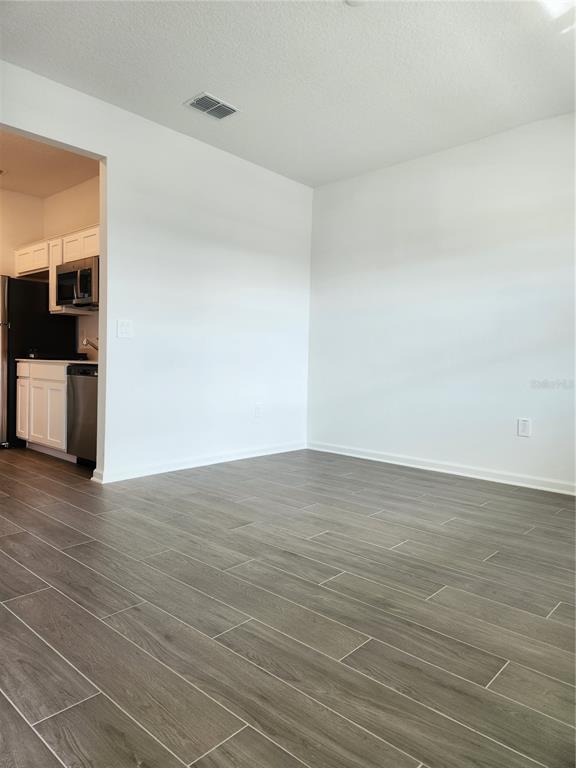 An empty dining area with wood-look tile flooring opens into a kitchen with white cabinets — 997 WATERFALL BOULEVARD, DAVENPORT, FL