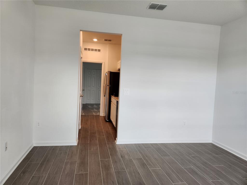 A view from a room with wood-look tile flooring looking through a doorway into a kitchen — 997 WATERFALL BOULEVARD, DAVENPORT, FL