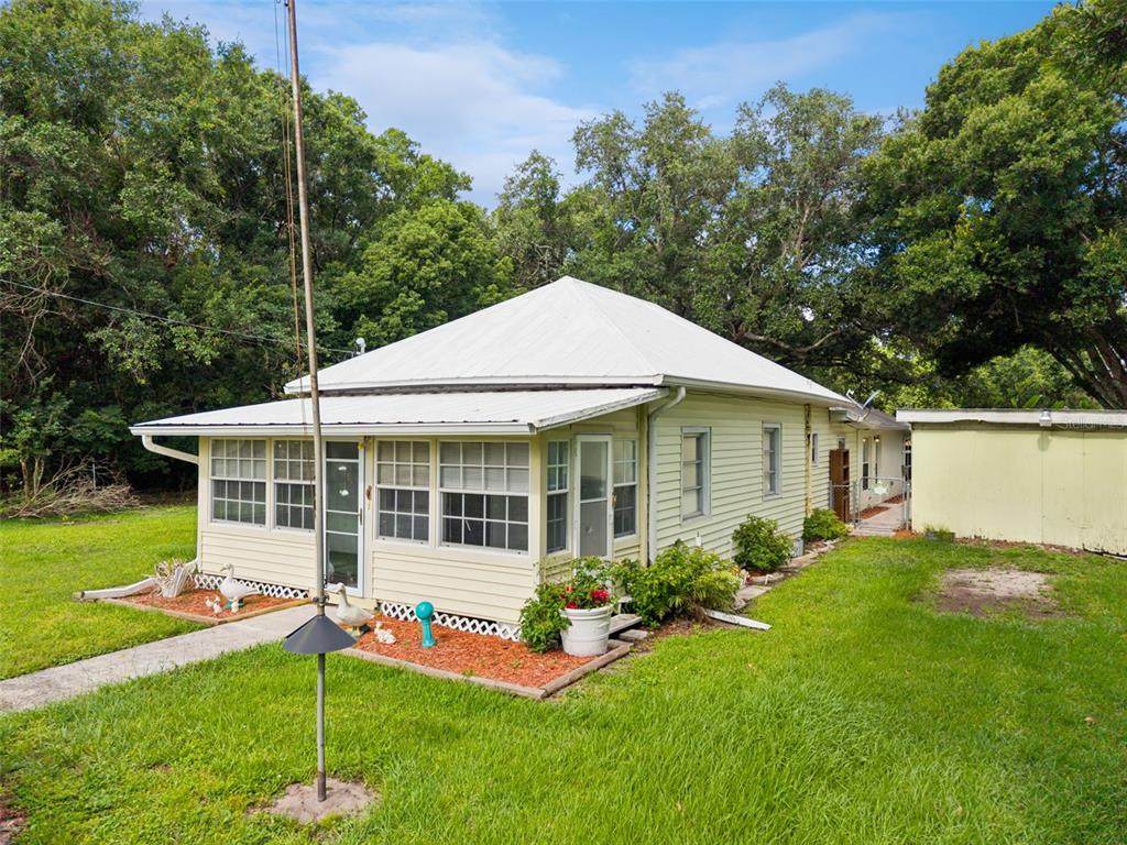 A light yellow house with a white metal roof and a screened-in front porch — 420 JACKS MEMORIAL RD, ST CLOUD, FL