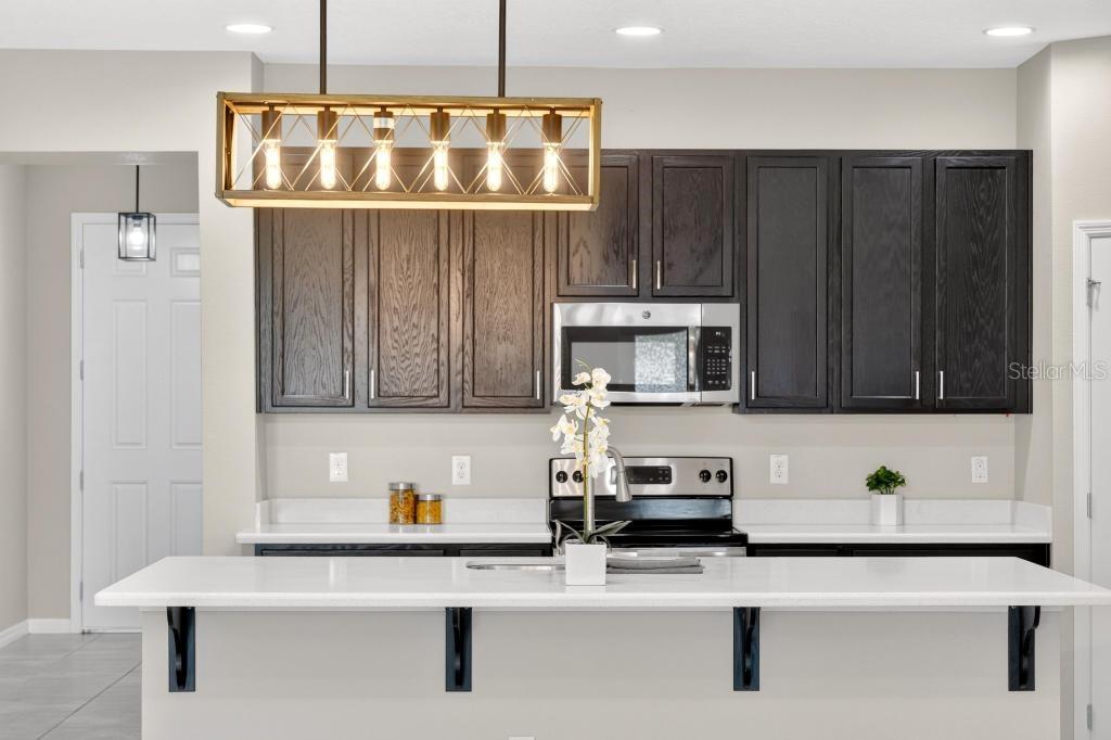 A kitchen features dark wood cabinets, white countertops, a large island, and a rectangular pendant light — 409 MERRY BROOK CIRCLE, SANFORD, FL