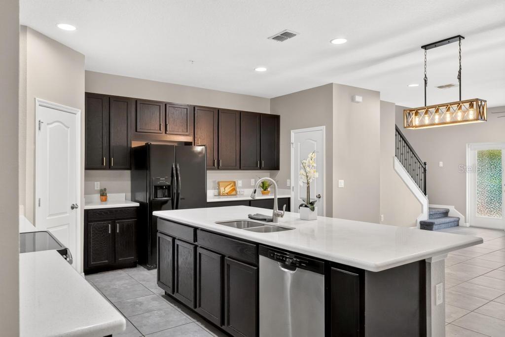 A kitchen with dark cabinets, white countertops, a central island, and a stainless steel dishwasher — 409 MERRY BROOK CIRCLE, SANFORD, FL