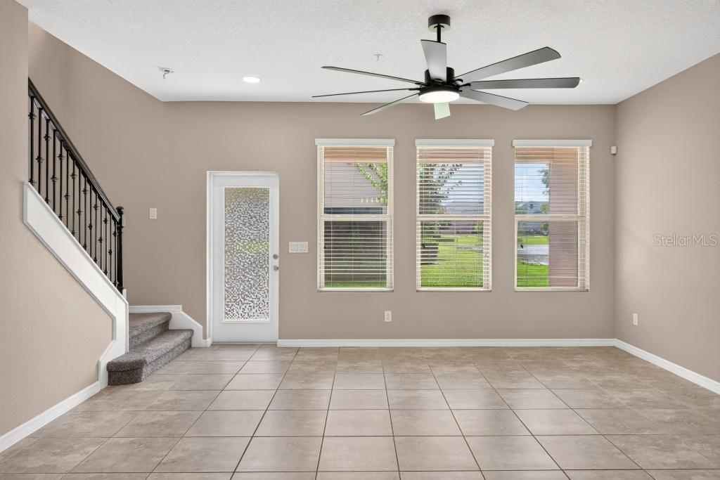 A living area features tile flooring, a ceiling fan, a staircase, and three large windows — 409 MERRY BROOK CIRCLE, SANFORD, FL