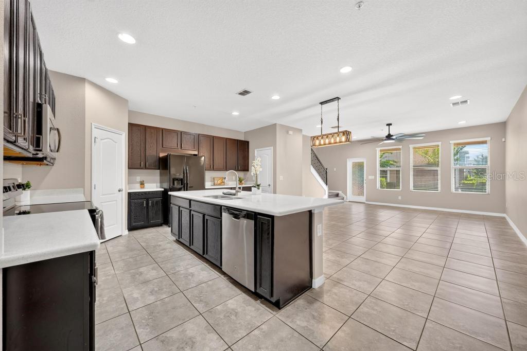 A kitchen with dark cabinets, a large white island, and tile flooring in an open space — 409 MERRY BROOK CIRCLE, SANFORD, FL
