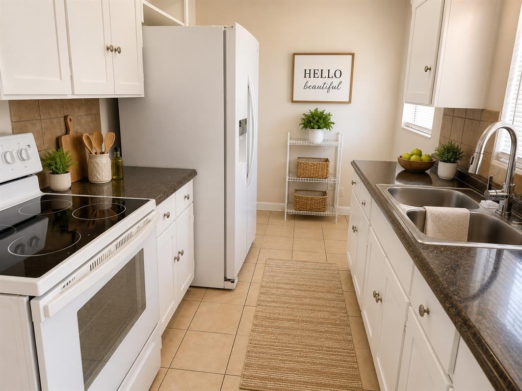 A kitchen with white cabinets, dark countertops, white appliances, and a tile floor — 14 JAPONICA DRIVE, ORLANDO, FL