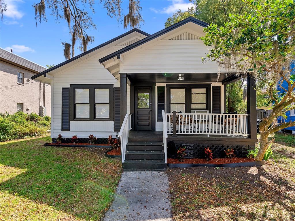 A white bungalow with black trim and a front porch sits on a grassy lot — 412 E HARWOOD STREET, ORLANDO, FL