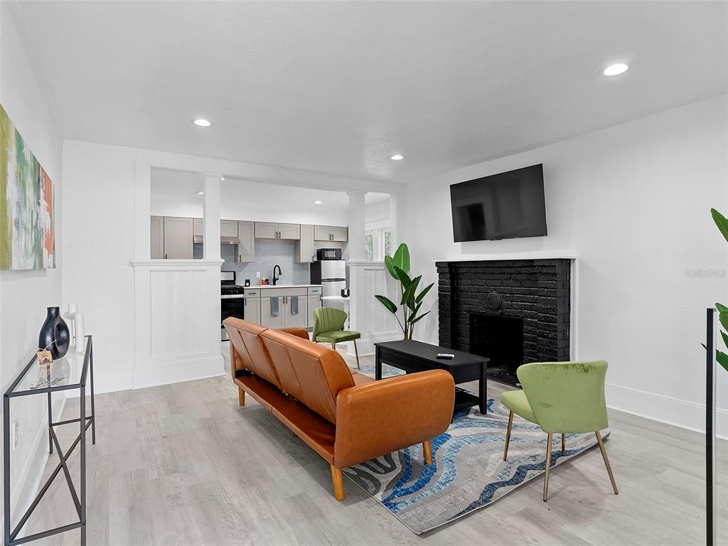 A living room with a black brick fireplace, brown sofa, and an open kitchen beyond — 412 E HARWOOD STREET, ORLANDO, FL