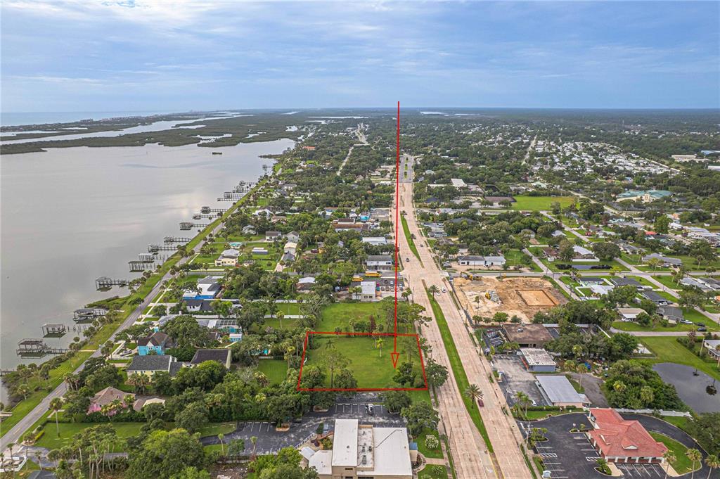 An aerial view shows a vacant, rectangular grassy lot outlined in red next to a road — 4491 S RIDGEWOOD AVENUE, PORT ORANGE, FL