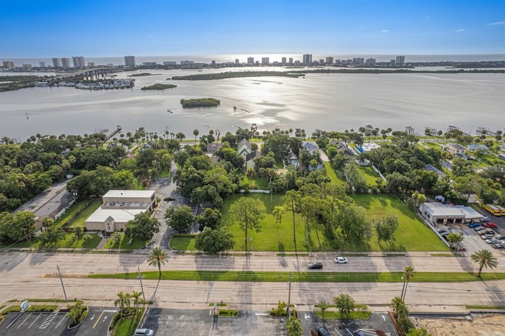 An aerial view shows a vacant grassy lot situated between two buildings near the water — 4491 S RIDGEWOOD AVENUE, PORT ORANGE, FL