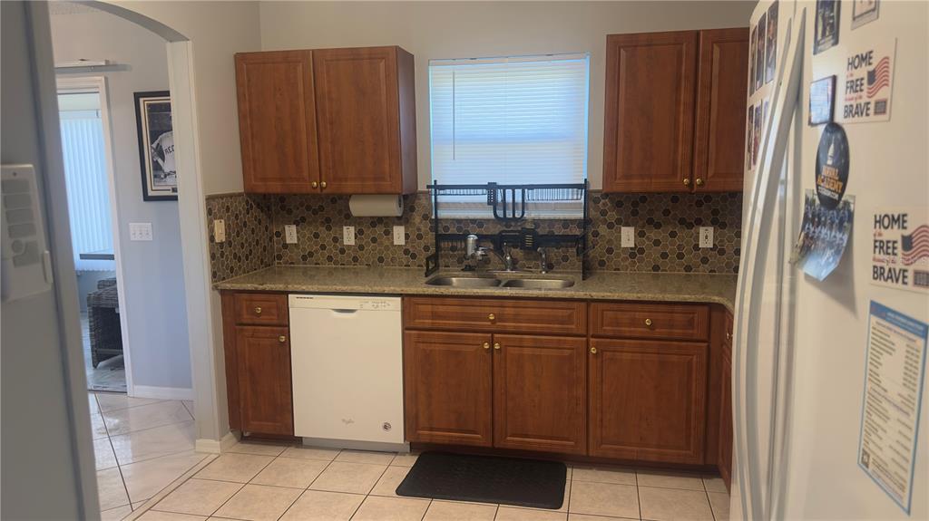 A kitchen with wood cabinets, a tiled backsplash, a dishwasher, and a double sink — 2259 MARGARITA DRIVE, THE VILLAGES, FL