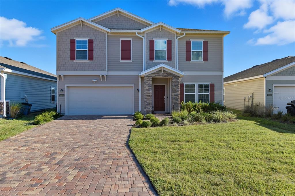 A two-story suburban house with a brick paver driveway and a stone-accented front entrance — 9852 LEMON BALM WAY, JACKSONVILLE, FL