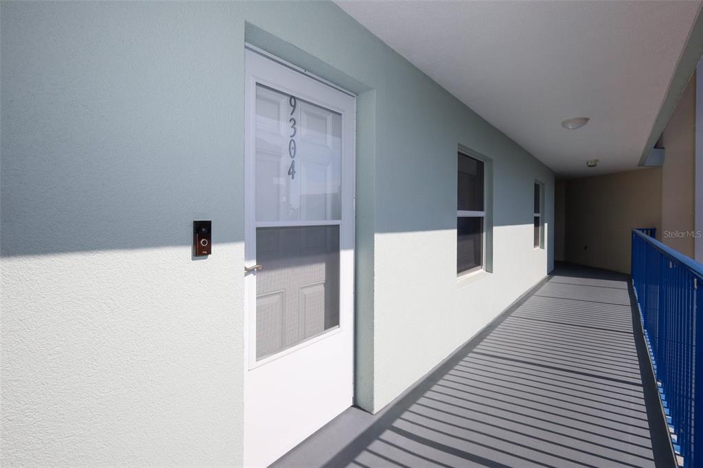 A view of an apartment entrance door with a storm door on an outdoor walkway — 5300 S ATLANTIC AVE UNIT 9-304, NEW SMYRNA BEACH, FL