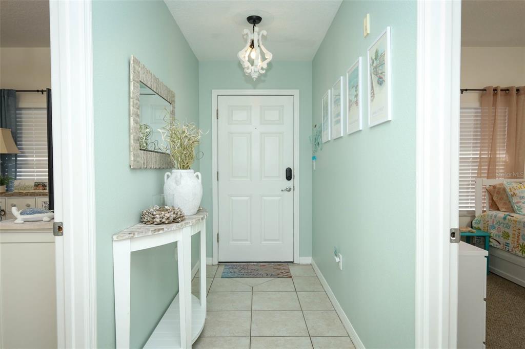 A bright entryway features light blue walls, a white console table, and a white door — 5300 S ATLANTIC AVE UNIT 9-304, NEW SMYRNA BEACH, FL